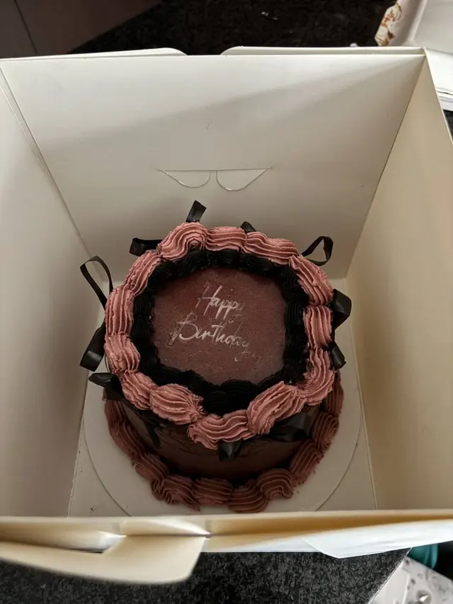 Pink and black ribbon cake with Happy Birthday plaque
