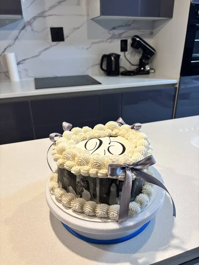 Cream 25th birthday cake with photo tier and ribbon